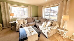 A living room with a sectional sofa, a coffee table, two side tables, and a lamp. - Westport Beach Hideout (West Fargo)