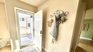 A hallway with a door leading outside, a wall-mounted decorative piece, and a rug on the floor. - Westport Beach Hideout (West Fargo)