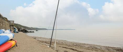 Ein Strand mit einer Mole, Booten und einem klaren Himmel.