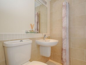 A bathroom with two sinks, a toilet, a mirror, and a shower curtain. - Little Trevallan (Looe)