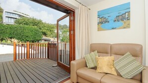 A balcony with a wooden floor and a glass door leading outside. - Little Trevallan (Looe)