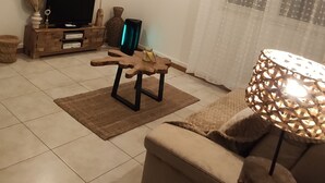 A living room with a sofa, a coffee table, a TV stand, and a lamp.