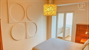 Un dormitorio con cama, cómoda de madera, balcón con barandilla y decoración en las paredes.