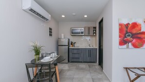 A compact kitchen with a dining area, a microwave, a refrigerator, and a painting of a flower on the wall.