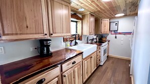 A kitchen with wooden cabinets, a coffee maker, a sink, and a stove. - NEW - Apache Cabin (Heber-Overgaard)