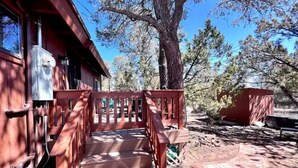 A wooden staircase leading to a cabin with a red exterior, surrounded by trees and a clear sky. - NEW - Apache Cabin (Heber-Overgaard)