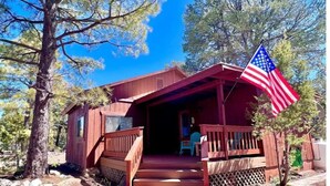 A wooden cabin with a porch, steps, and an American flag. - NEW - Apache Cabin (Heber-Overgaard)