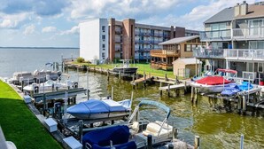 A marina with boats docked, a grassy area, and buildings with balconies. - Ocean City Bayfront Ponte Vista (Ocean City)