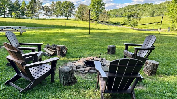 Un espace extérieur verdoyant, aménagé avec des fauteuils Adirondack et un foyer.