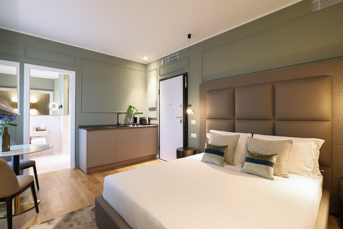 Una habitació d'hotel moderna amb un llit gran, una taula de treball i una cuineta.