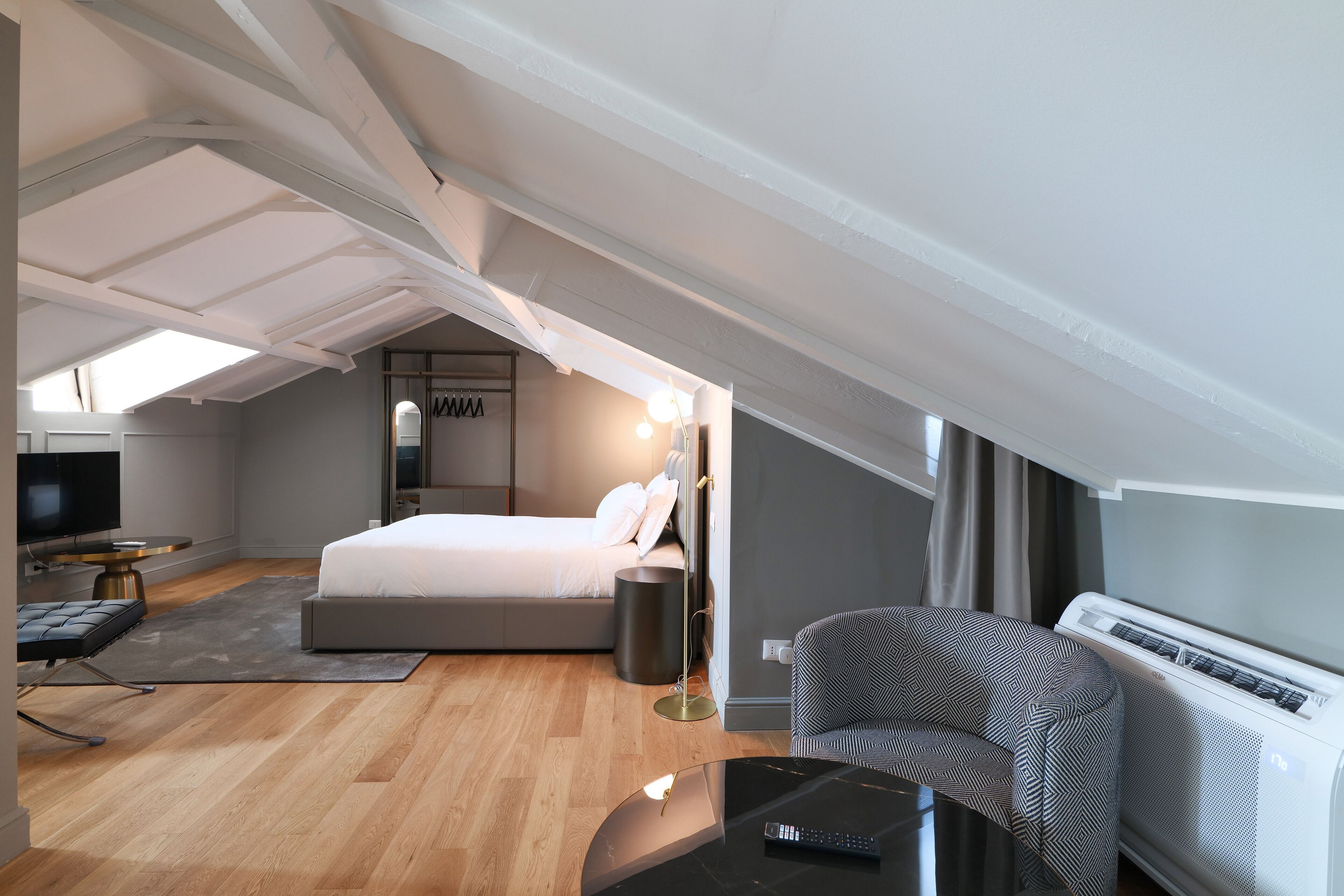 Un dormitorio moderno con cama, mesita de noche, lámpara y televisor.