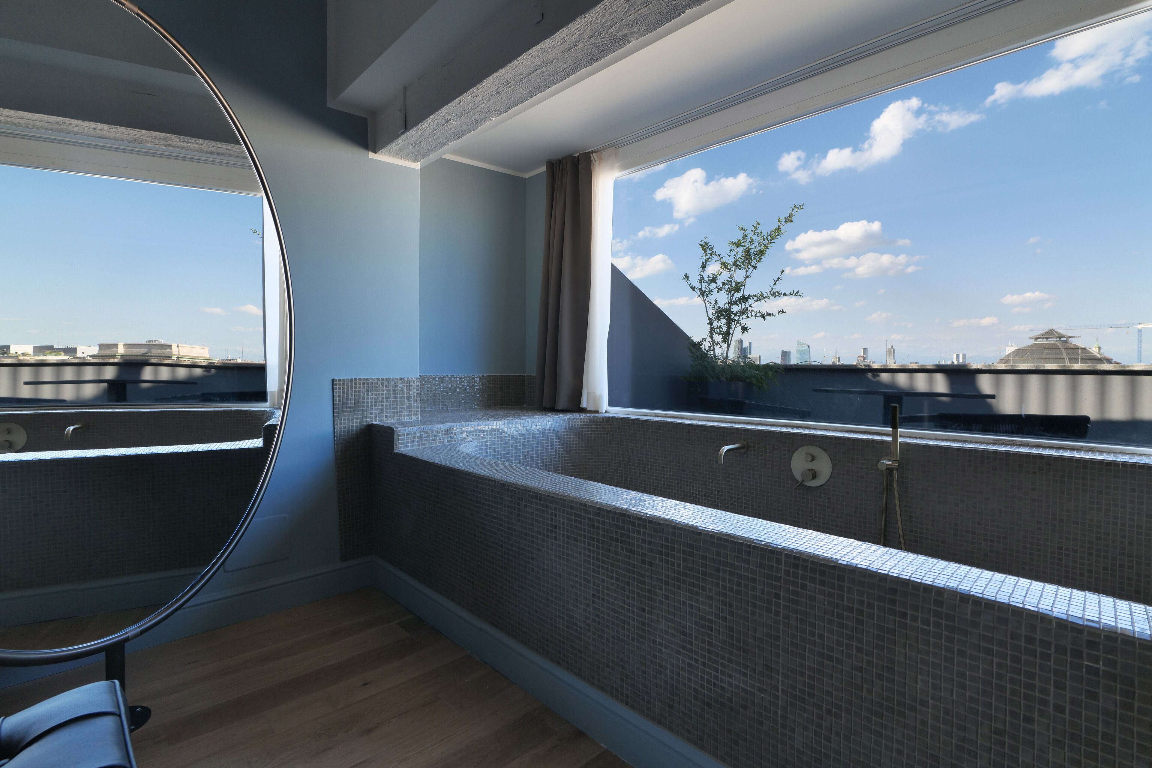 Uma casa de banho moderna com uma janela ampla, uma banheira e vista para o horizonte da cidade.