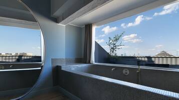 A modern bathroom with a large window, a bathtub, and a view of the city skyline.