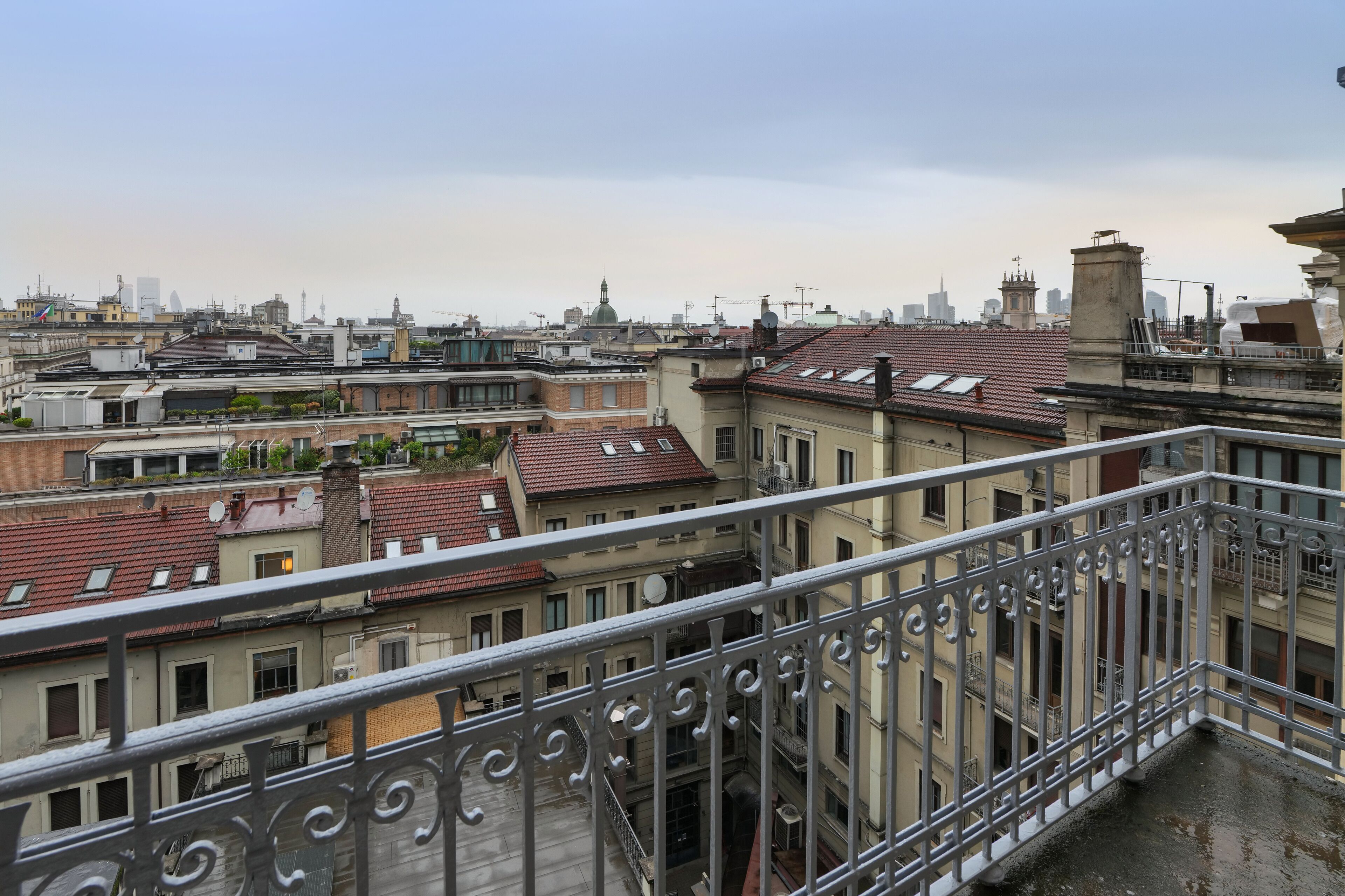 Blick vom Balkon auf eine Stadtlandschaft mit mehreren Gebäuden, darunter ein markanter Turm mit einer Kuppel.