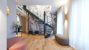 Een modern interieur met een spiltrap, houten vloer en een zithoek met een plant.