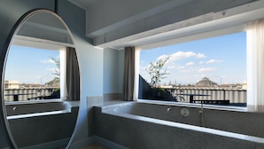 Een moderne badkamer met een groot raam, een bad en een spiegel.