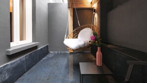 Een modern interieur met een hangstoel, een bank en een vaas met bloemen.