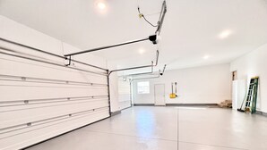 A spacious, well-lit room with a large white door, a broom leaning against the wall, and a ladder propped up. - New home, close to skiing, hunting, rodeos, hiking. Fenced yard, pet friendly. (Darby)