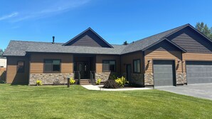 A modern two-story house with a stone foundation, a stone accent wall, and a well-maintained lawn. - New home, close to skiing, hunting, rodeos, hiking. Fenced yard, pet friendly. (Darby)