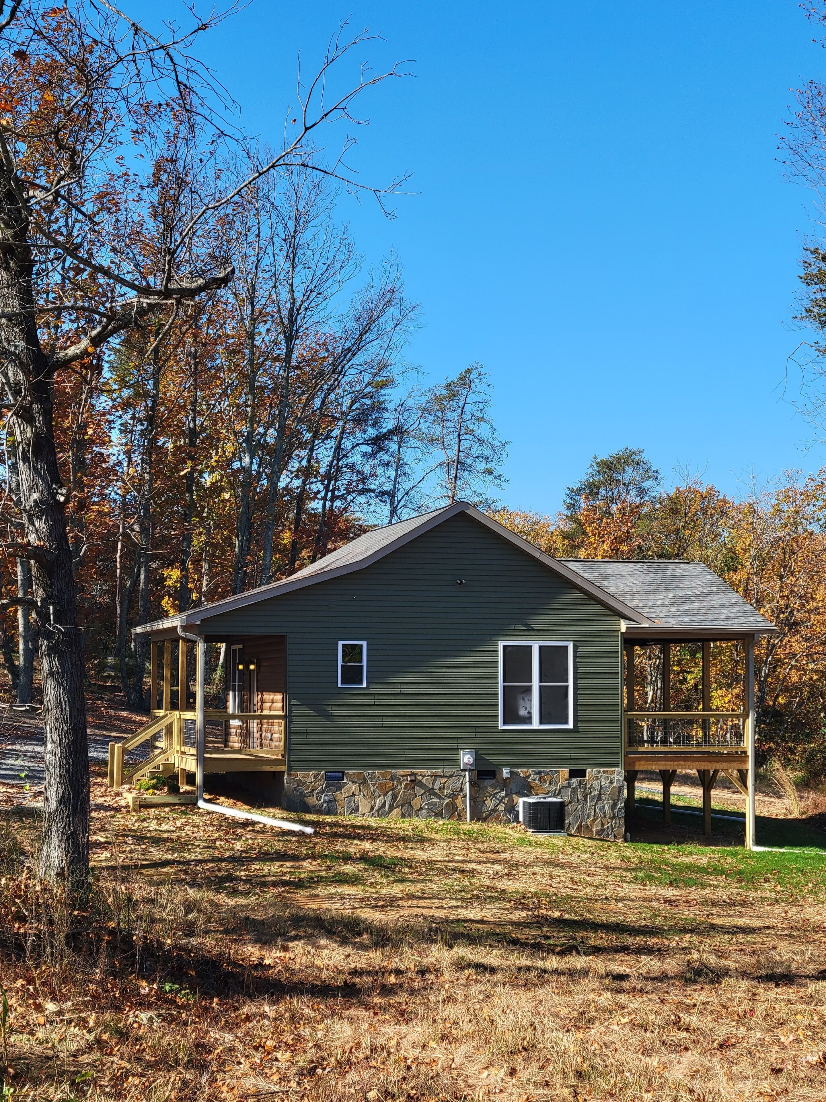 A rustic cabin with a stone foundation, a wooden deck, and a porch.