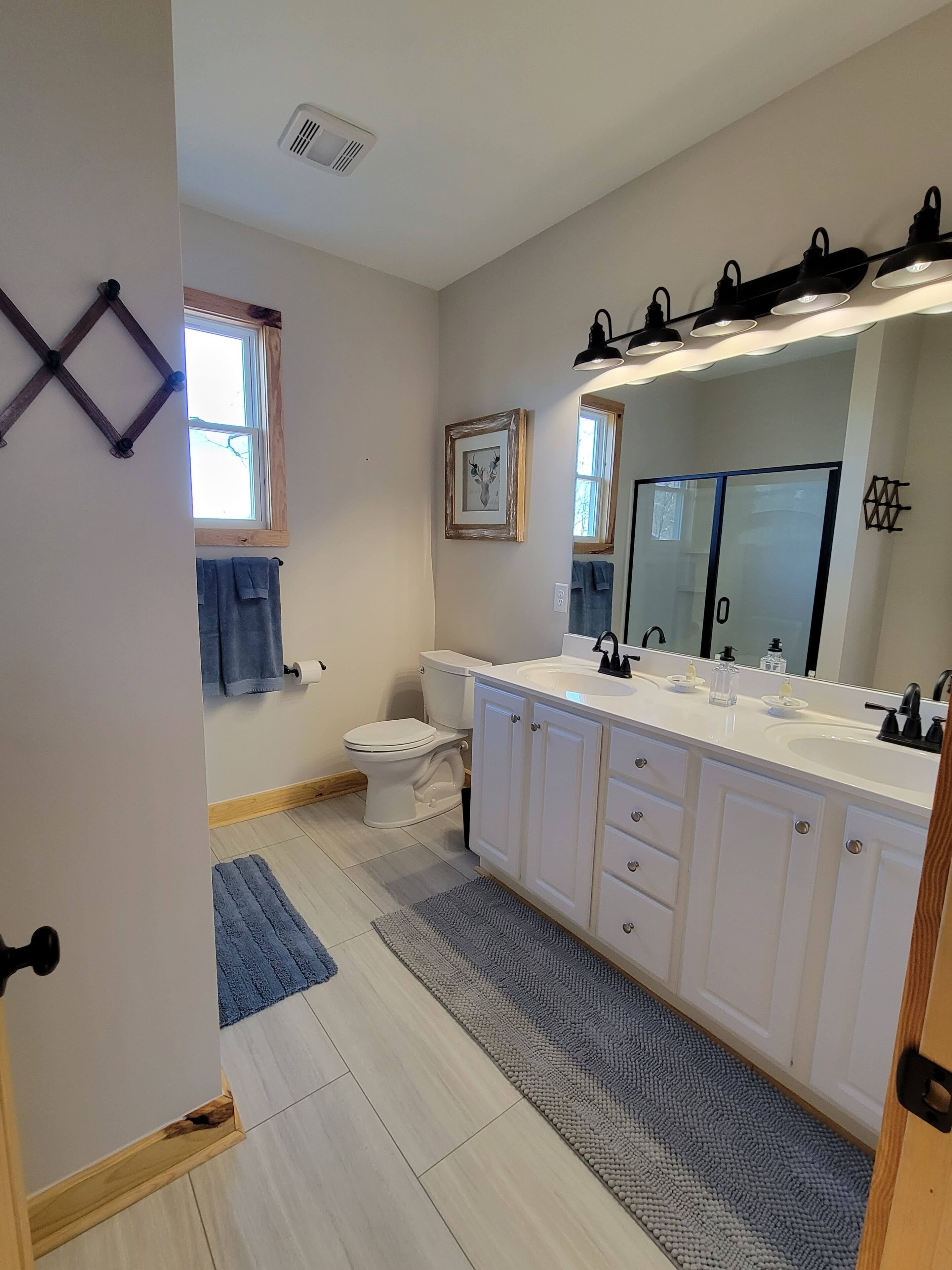 A modern bathroom with a white vanity, double sink, and a large mirror.