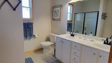 A modern bathroom with a white vanity, double sink, and a large mirror.