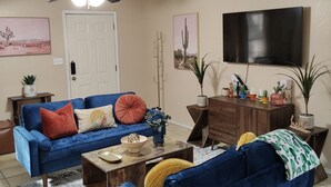 A living room with a blue sofa, a coffee table, a TV, and a ceiling fan.