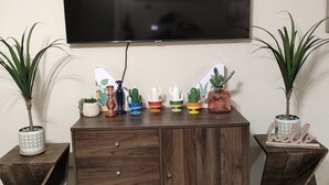 A wooden TV stand with a flat-screen TV mounted above it, flanked by two side tables with potted plants.