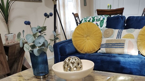 A wooden coffee table with a glass top, a decorative bowl, and a ceramic plate.