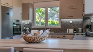 Een moderne keuken met een houten keukeneiland, een raam met uitzicht op groen, en geïntegreerde apparatuur.