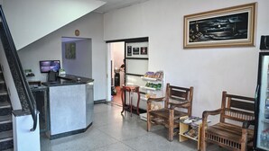 A reception area with a marble counter, wooden chairs, a framed artwork, and a refrigerator. - Hotel Bandeirantes (Sao Joao da Boa Vista)