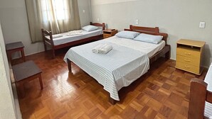 A room with two beds, a ceiling fan, a painting on the wall, and a wooden floor. - Hotel Bandeirantes (Sao Joao da Boa Vista)