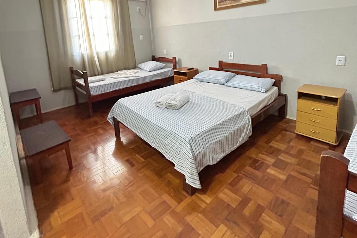 Une chambre avec deux lits, un ventilateur de plafond, un tableau au mur et un plancher en bois.