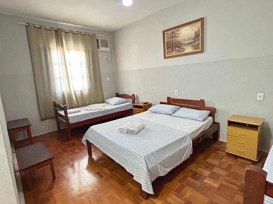 A room with two beds, a ceiling fan, a painting on the wall, and a wooden floor.