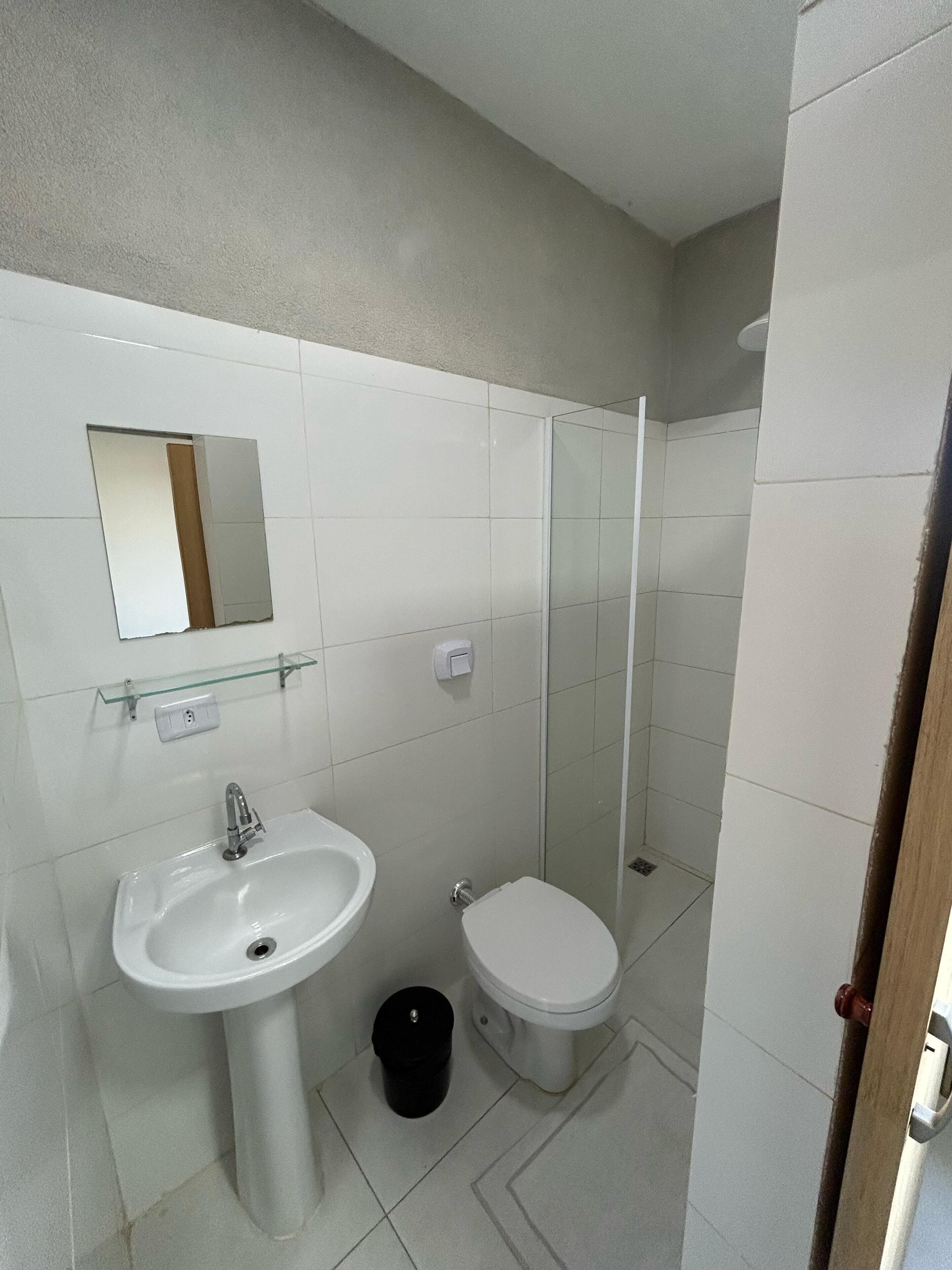 Un baño con lavamanos, inodoro y cabina de ducha de vidrio.