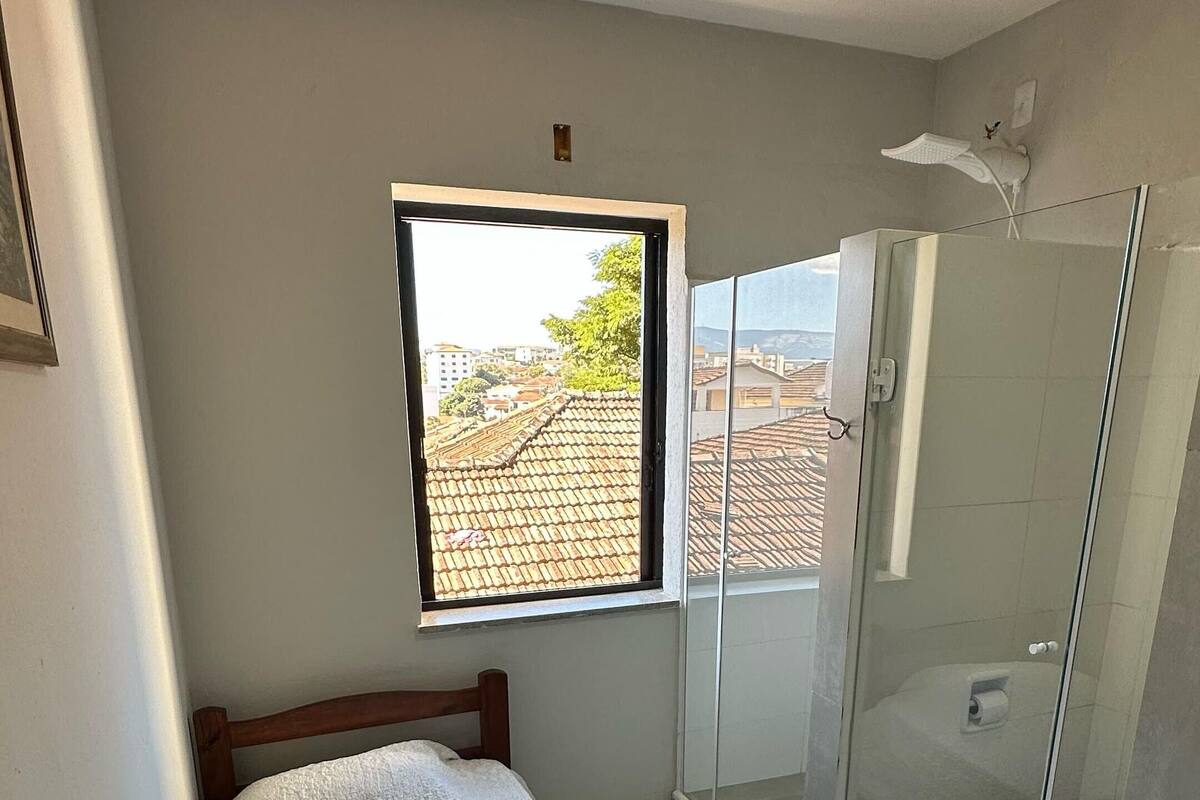 Une chambre à coucher avec un lit, une fenêtre et une douche fermée par des parois en verre.