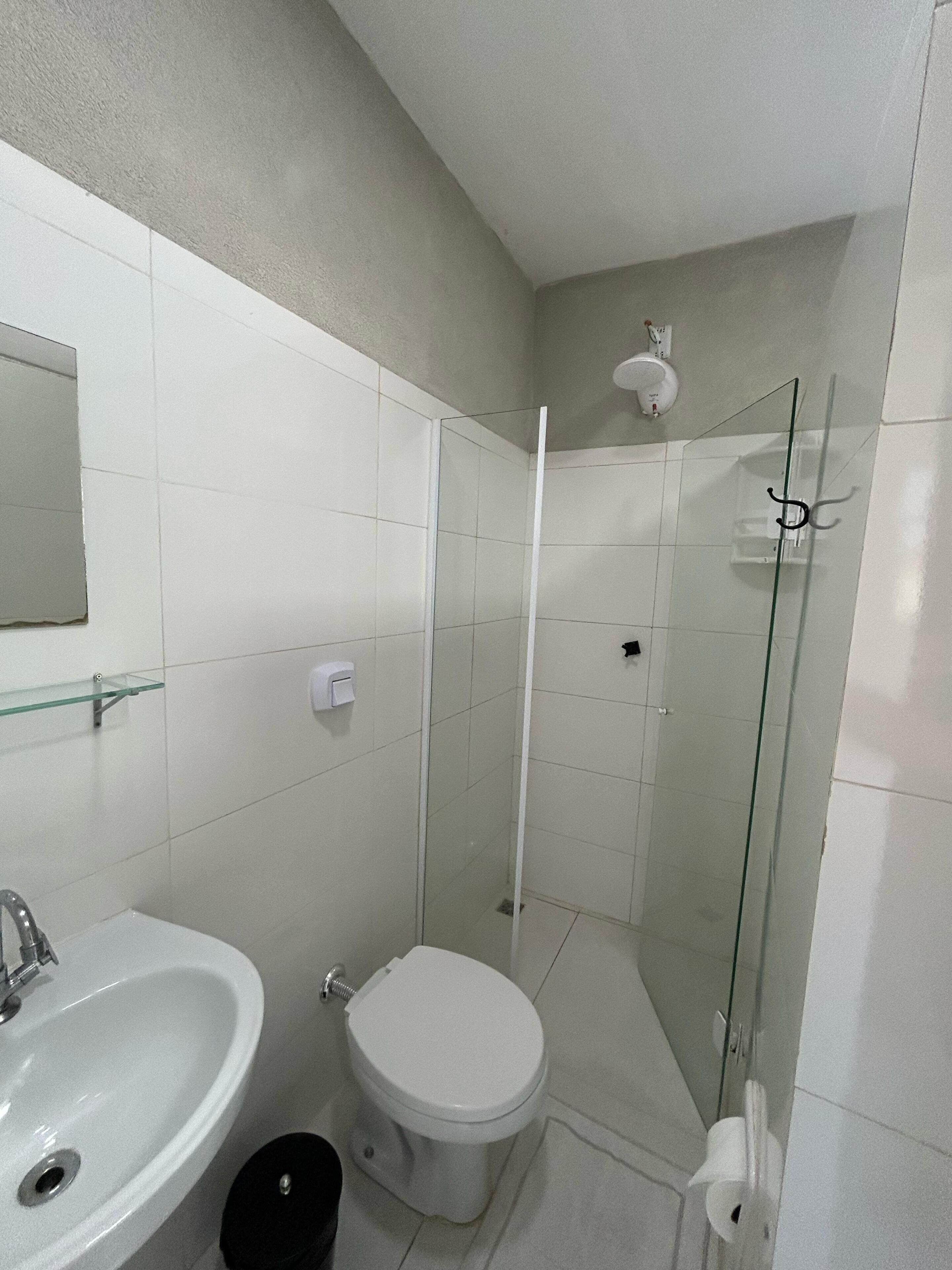 A bathroom with a toilet, sink, and glass shower enclosure.