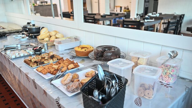 A buffet table with various food items and utensils. - Hotel Bandeirantes (Sao Joao da Boa Vista)