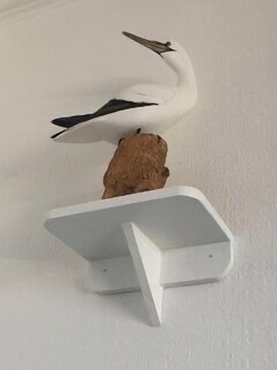 A white bird sculpture on a white wall.