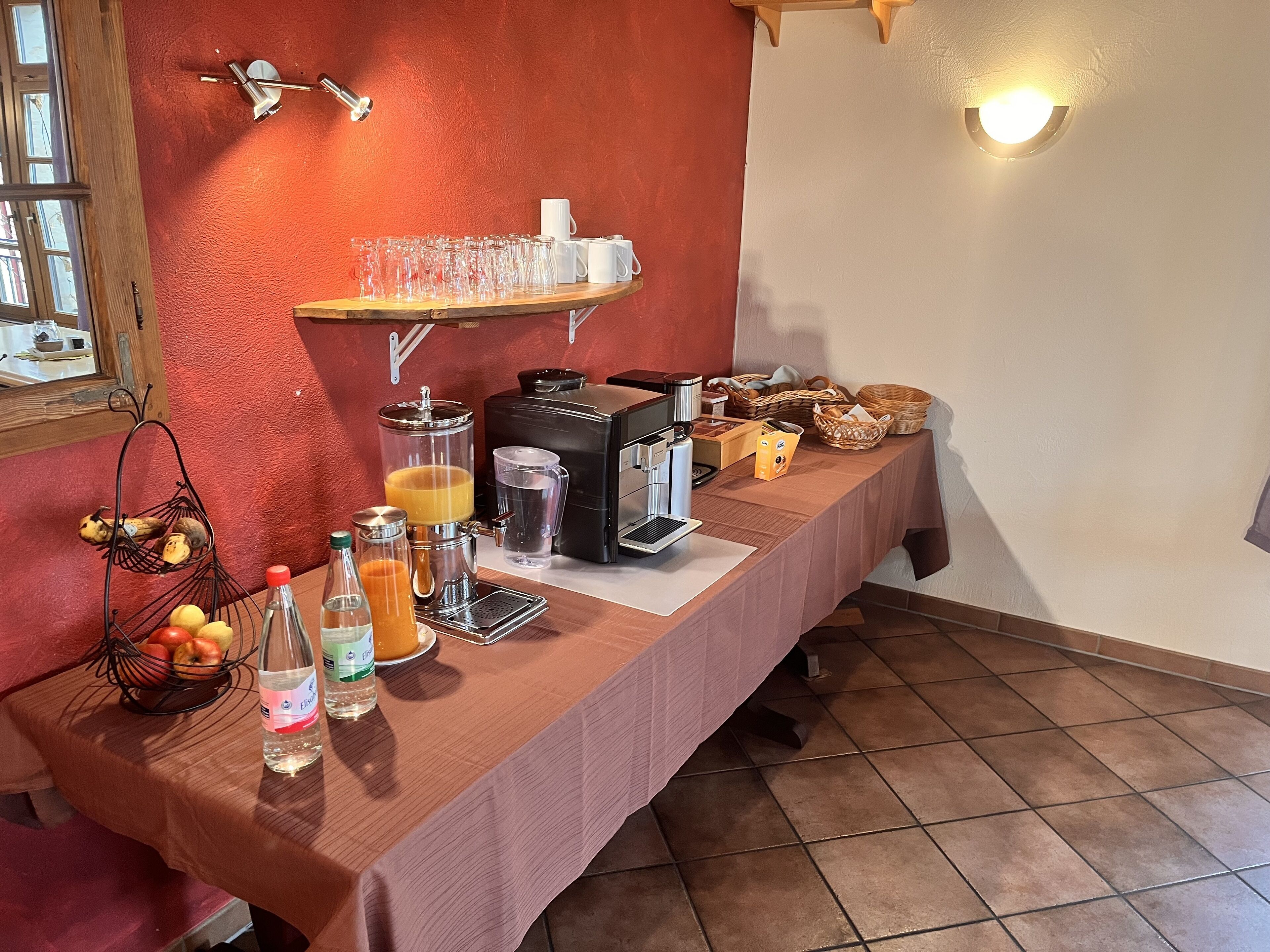 A breakfast bar with a coffee machine, juice dispenser, and various breakfast items.