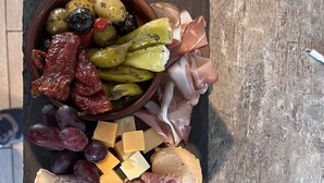 A charcuterie board with various cheeses, meats, grapes, olives, and pickles on a slate board. - Altstadt-Residenz Manz (Wachenheim an der Weinstrasse)