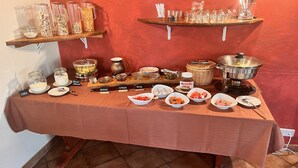 A buffet table with various food items and condiments, including jars of pickles, a bowl of fruit, and a container of Nutella. - Altstadt-Residenz Manz (Wachenheim an der Weinstrasse)