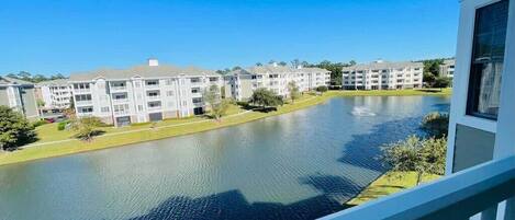 A view of a residential area with a body of water, multiple apartment buildings, and a balcony railing.