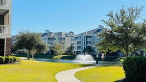 A residential building complex with a central water feature, a pathway, and well-maintained lawns. - Amazing Pond View condo + pool at MyrtleWoods (Myrtle Beach)
