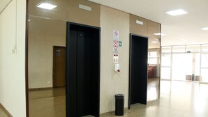 An elevator area with a trash bin, a handicap accessible door, and a sign indicating no smoking. - Days inn by Wyndham Uberlândia (Uberlandia)