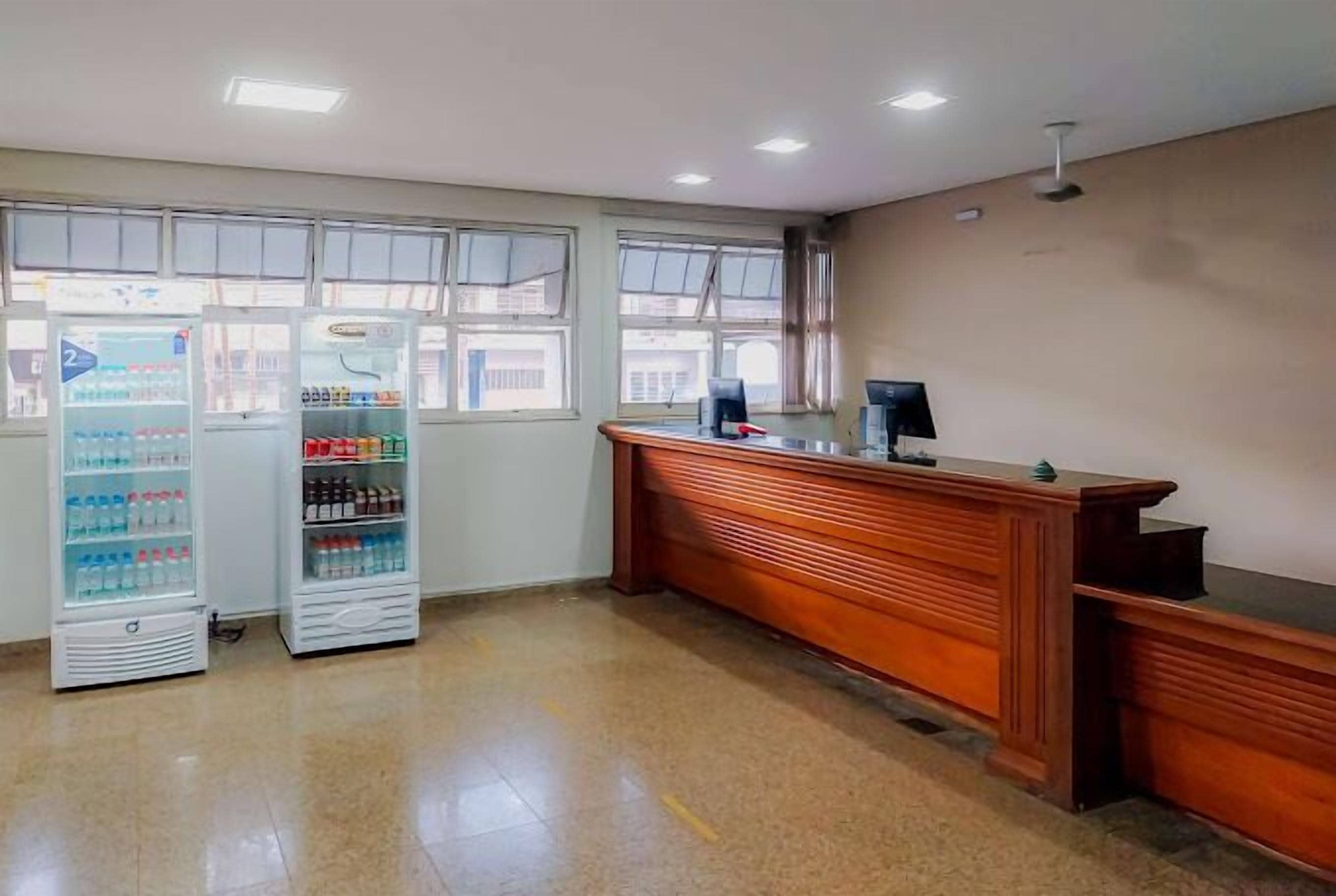 A reception area with a wooden reception desk, two vending machines, and large windows.