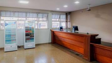 A reception area with a wooden reception desk, two vending machines, and large windows.