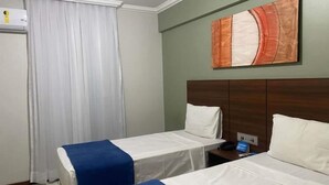 A hotel room with two beds, a nightstand, a painting on the wall, and a window with curtains. - Days inn by Wyndham Uberlândia (Uberlandia)