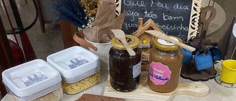 A wooden cutting board with cheese and meat, jars of preserves, and a chalkboard with writing.