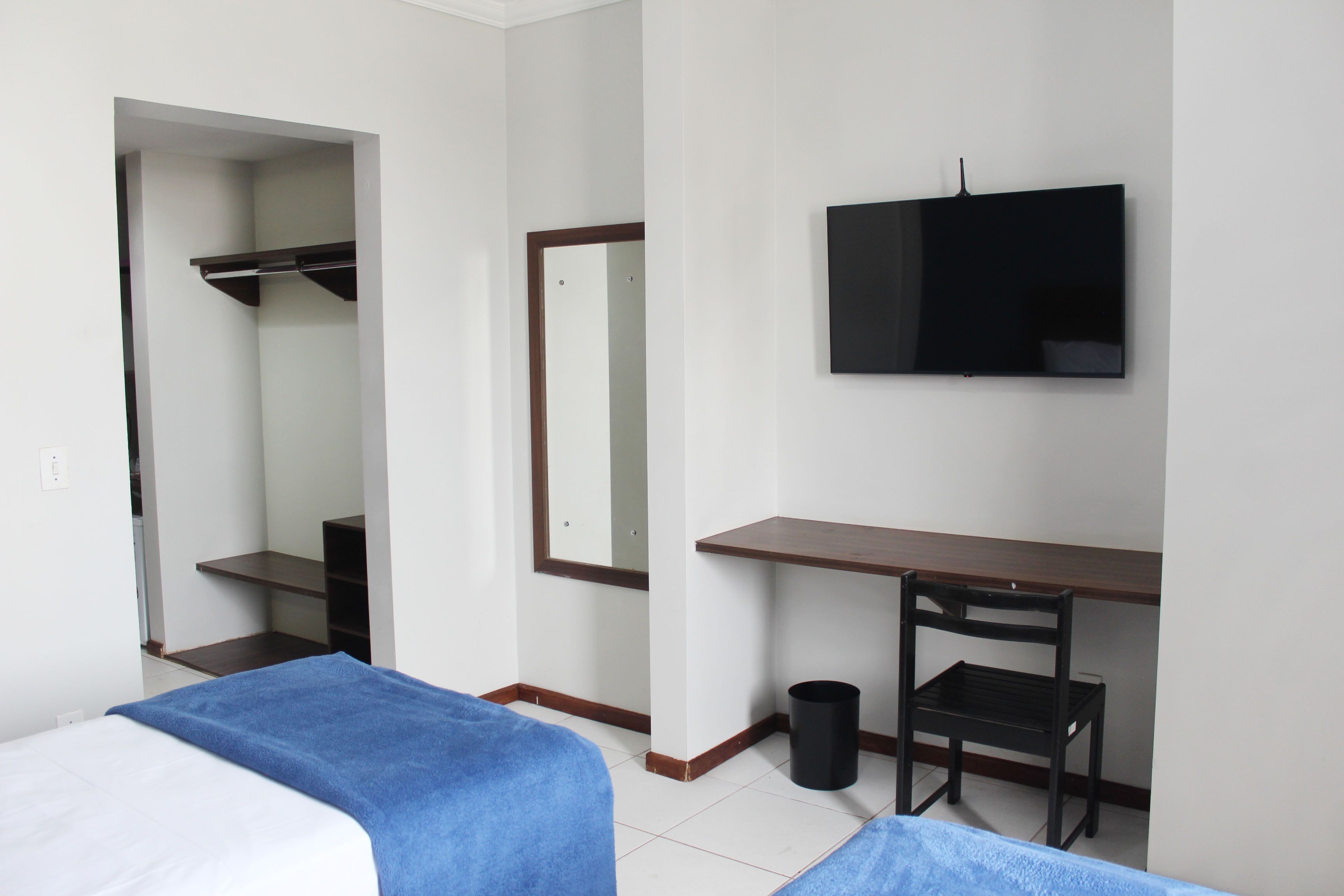 Une chambre d’hôtel avec un lit, un bureau, une chaise, une télévision et un miroir.
